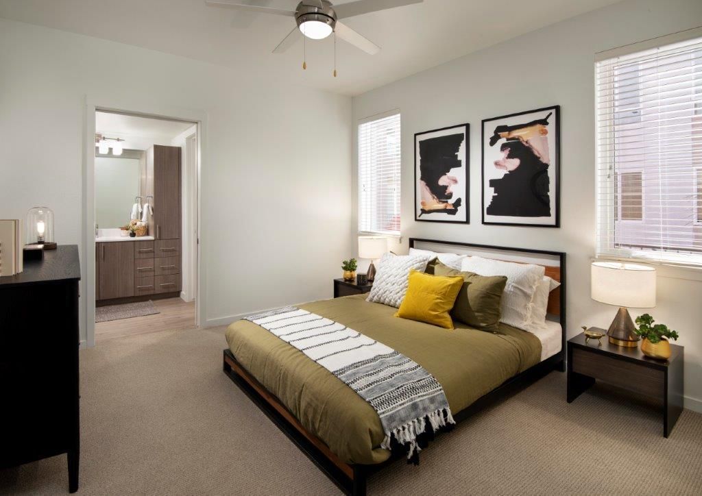 Bedroom in a modern apartment with a bed, two nightstands, and framed art.