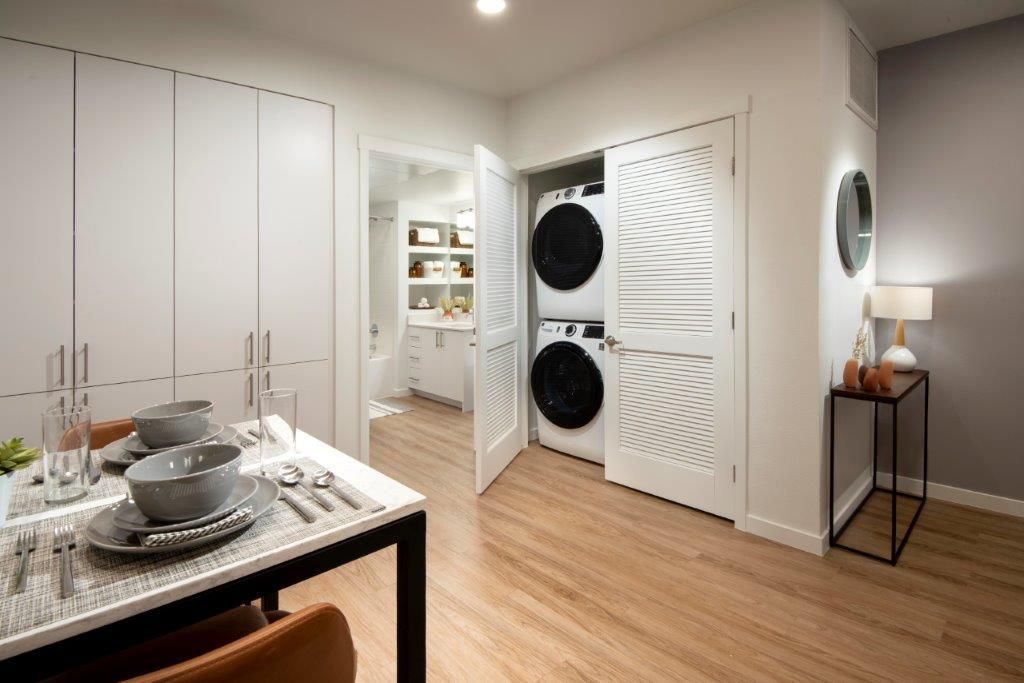 Interior view of an apartment with a stacked washer/dryer in a laundry closet beside a dining area.