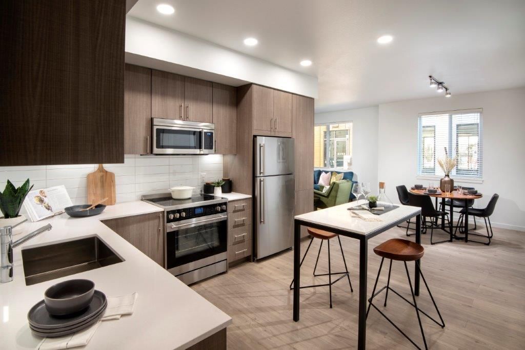 Open-concept kitchen with stainless-steel appliances and an island in a modern apartment.