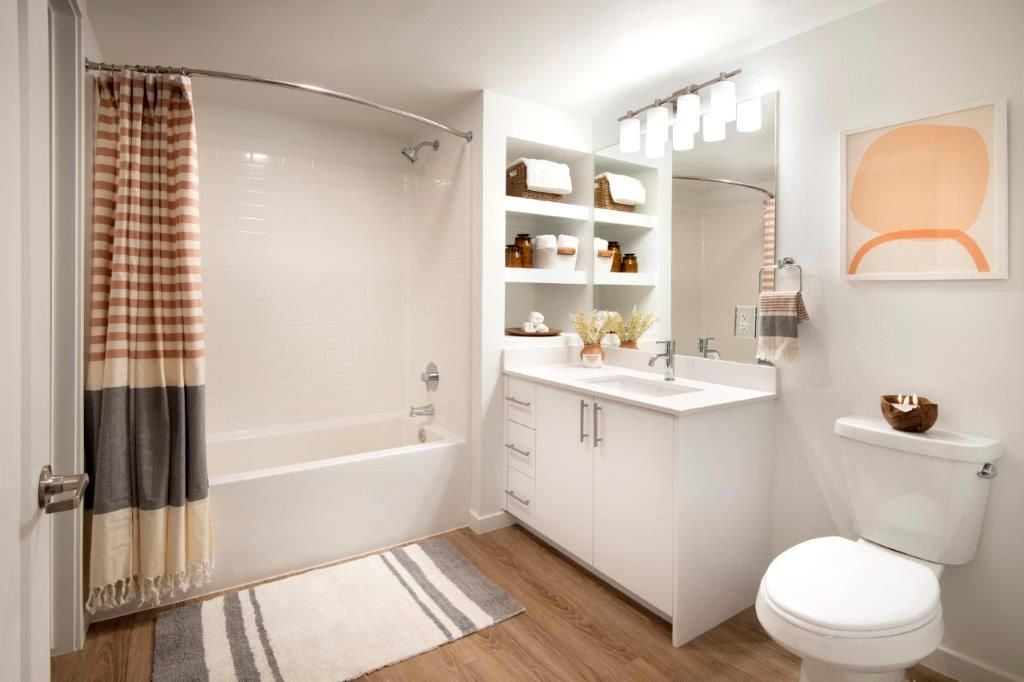 Modern bathroom with tub/shower, white vanity, open shelving, and neutral decor.