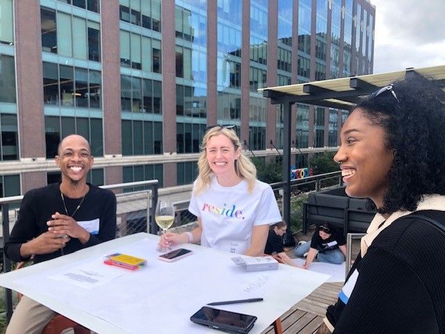 A group of people are sitting at a table talking to each other.