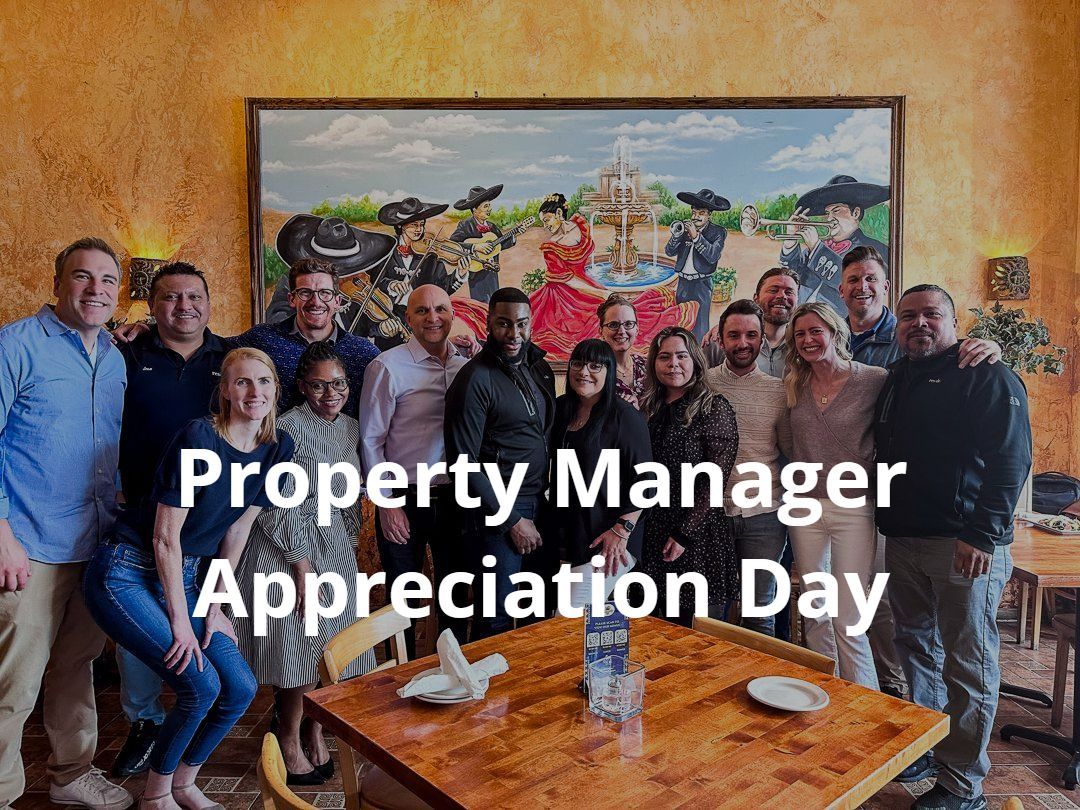 A group of people are posing for a picture in front of a painting on property manager appreciation day.
