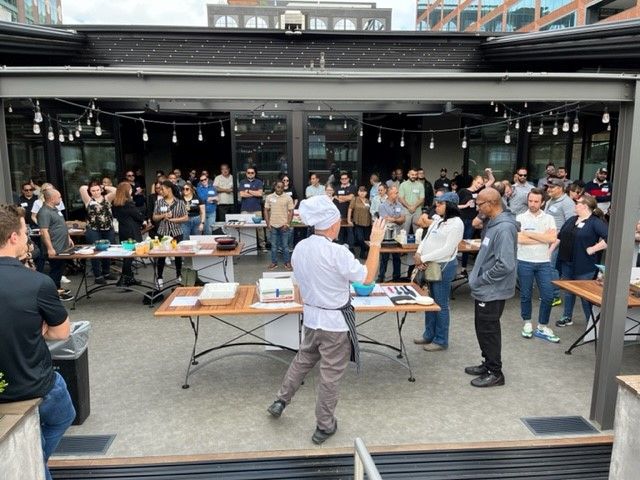 A man in a chef 's hat is standing in front of a crowd of people.