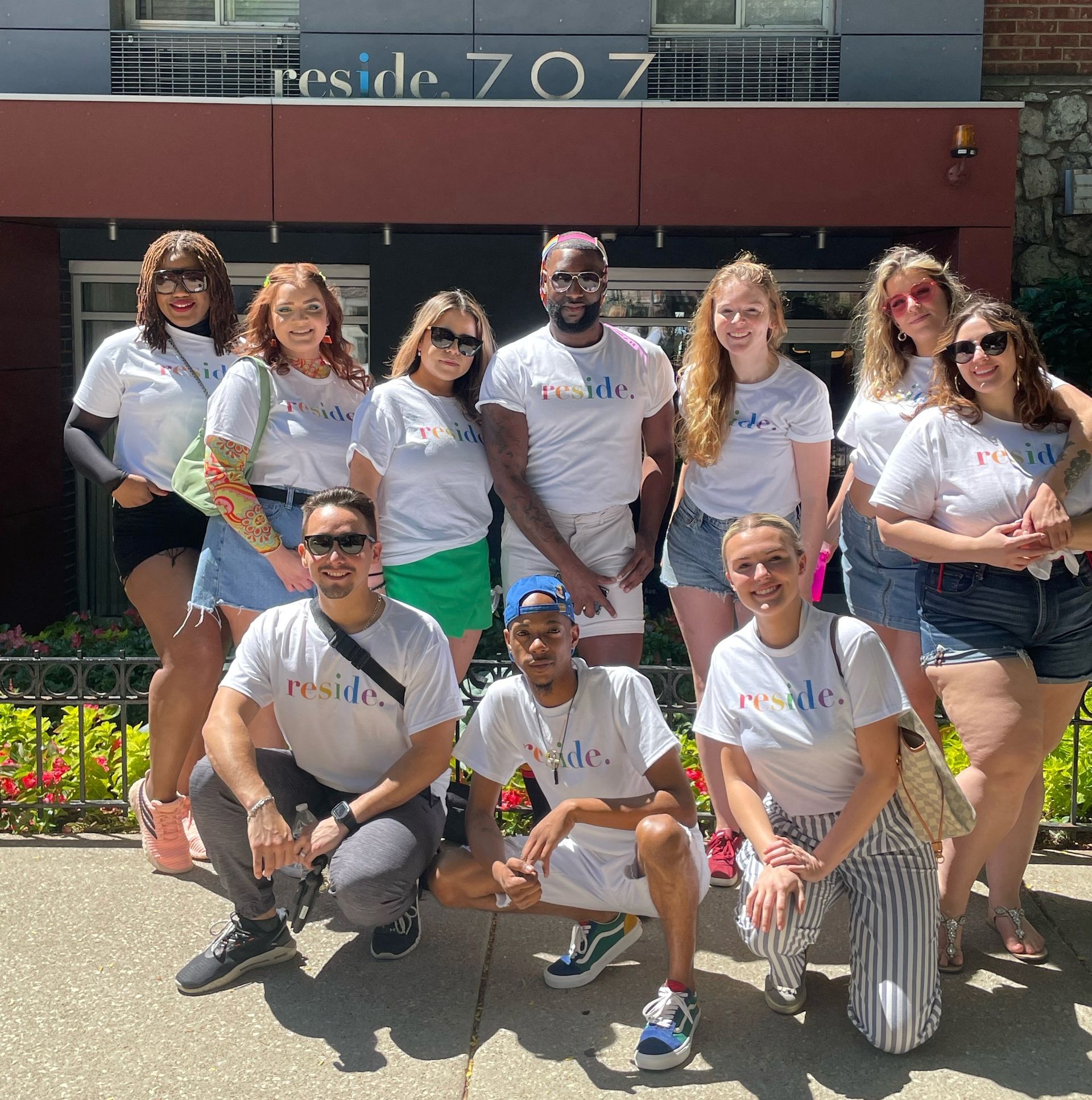 A group of people posing for a picture in front of a building that says reside 707