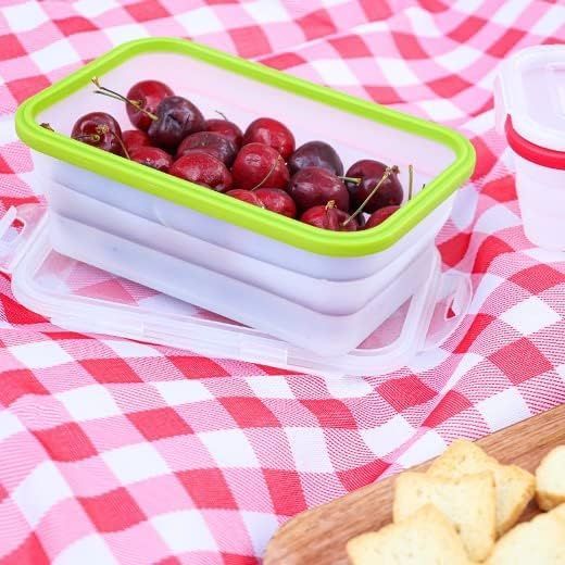 Cherries in a collapsible green and clear rectangular food container, sitting on a red and white checkered picnic blanket.