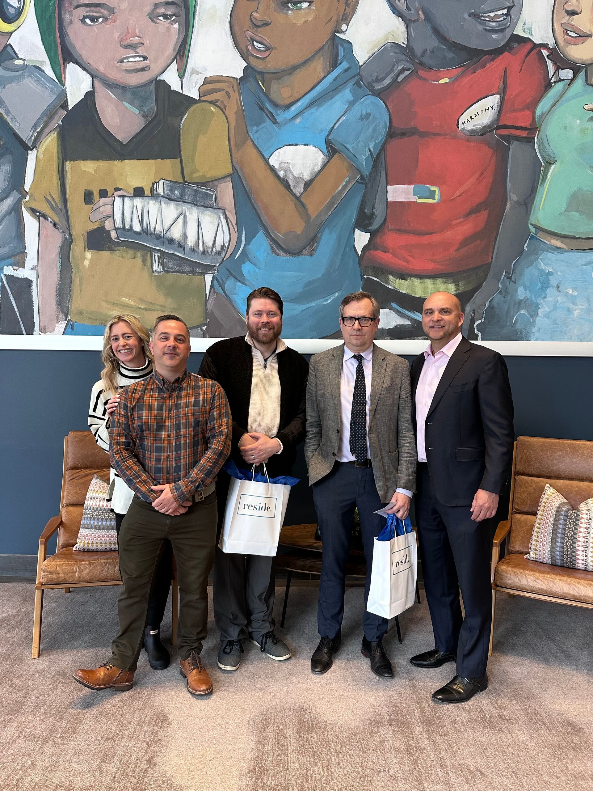 A group of people are posing for a picture in front of a mural.