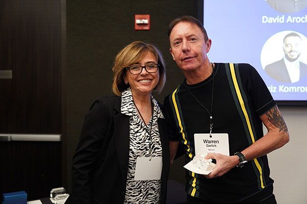 A man and a woman are posing for a picture in front of a screen that says david arnold