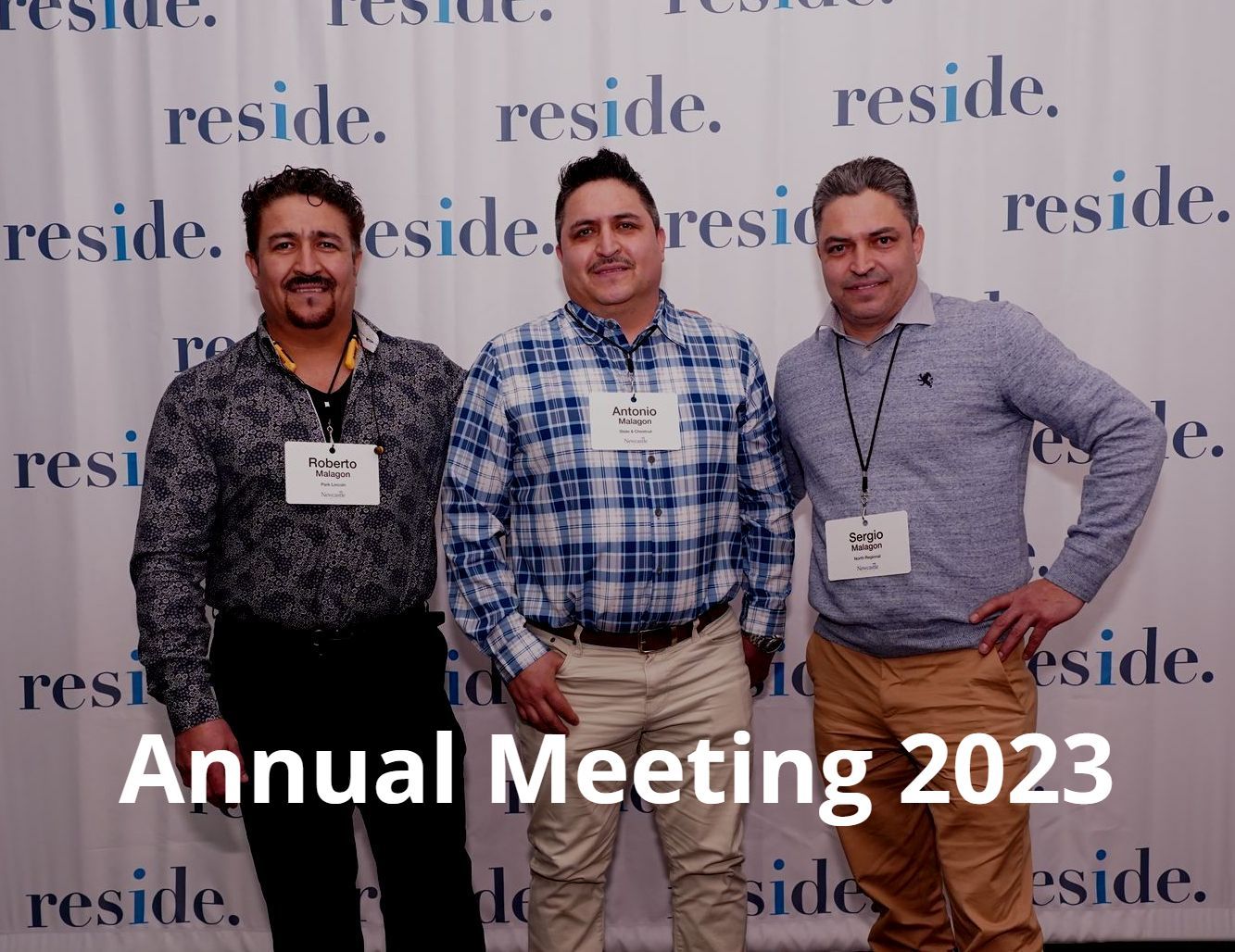 Three men standing in front of a wall that says annual meeting 2023