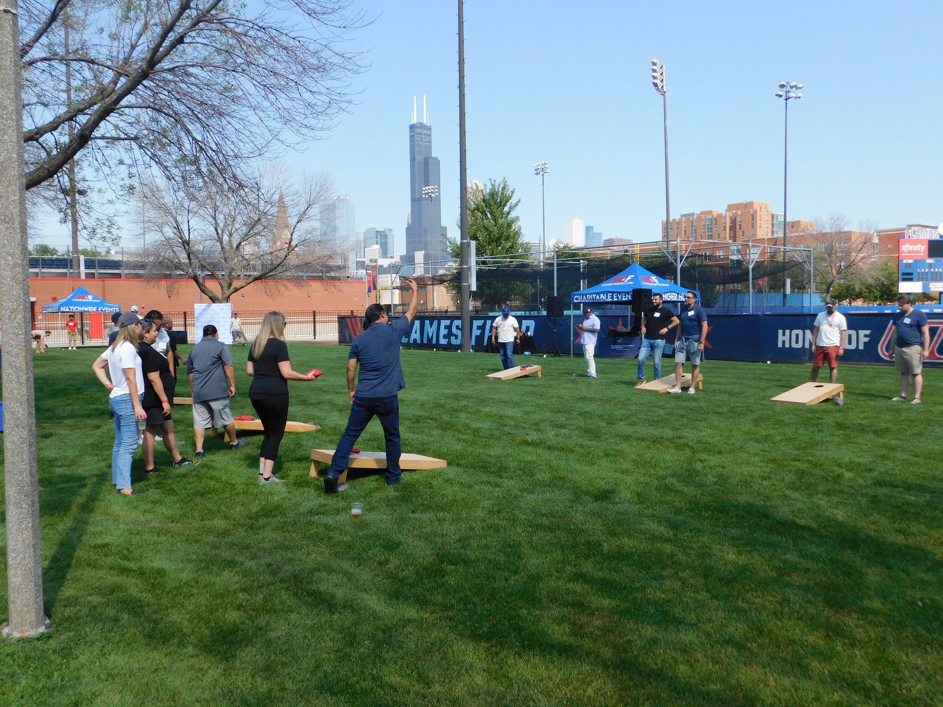 A group of people are playing cornhole in a park.