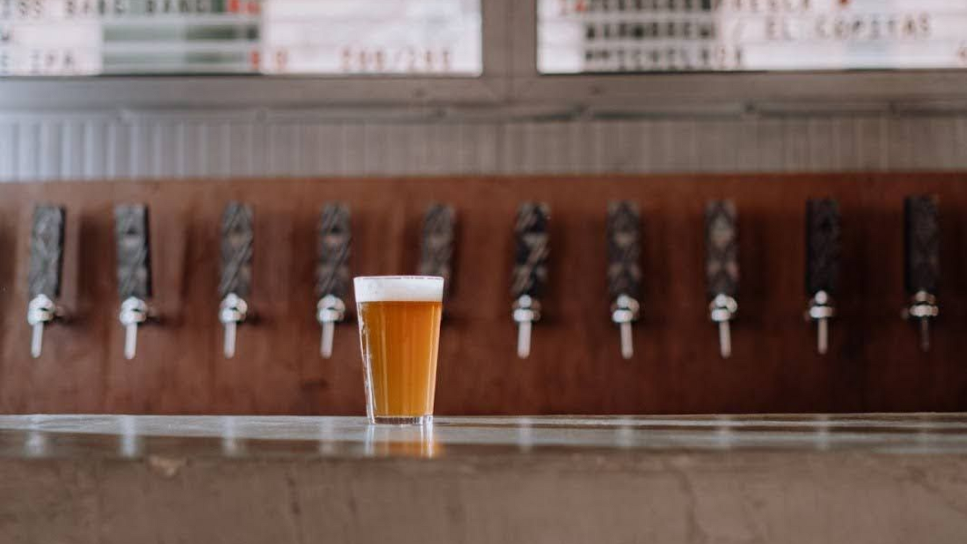 A cup of beer in front of bear tab.