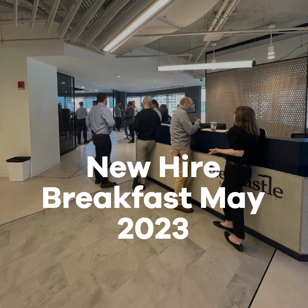 A group of people standing in a lobby with the words new hire breakfast may 2023