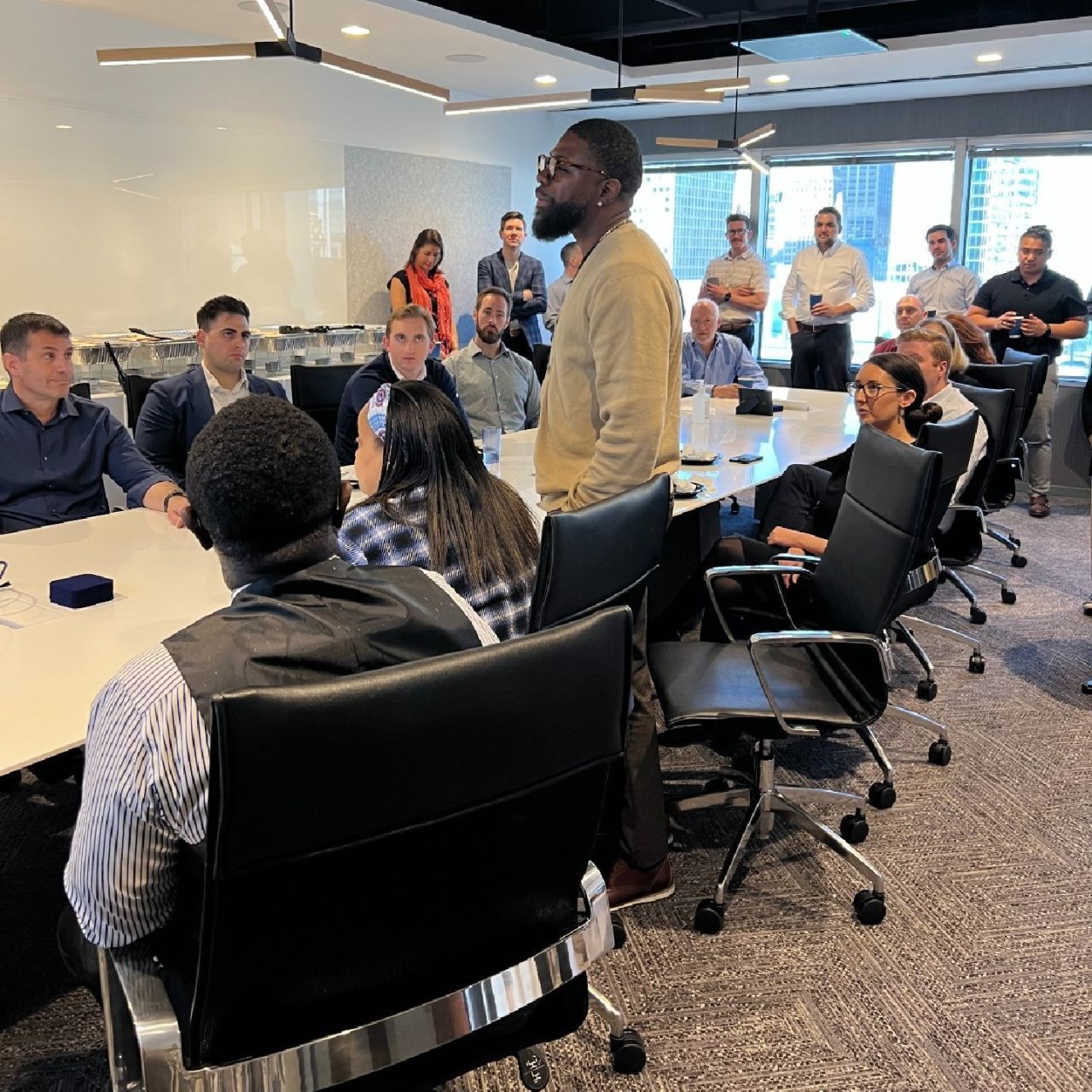A group of people are sitting around tables in a conference room