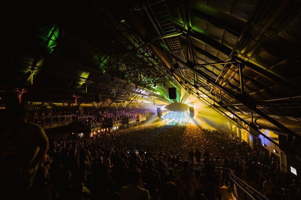 A large crowd of people are watching a concert in a dark stadium.