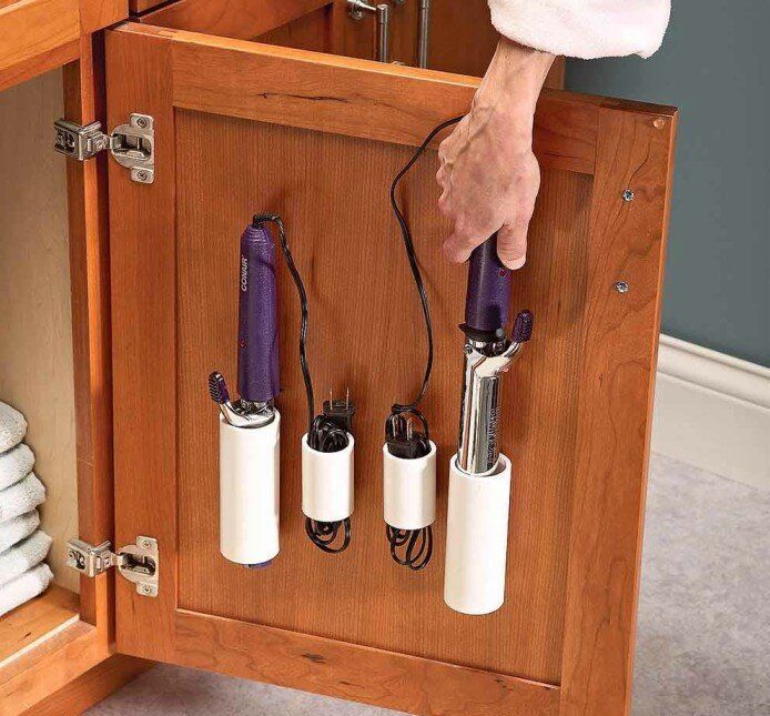 A person is holding a hair curler in a cabinet