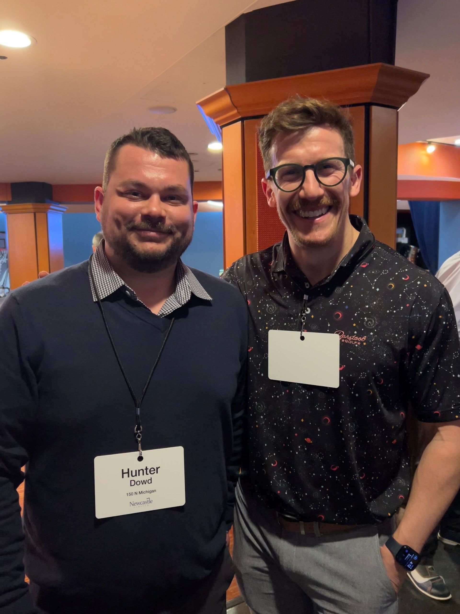 Two men are posing for a picture and one has a name tag that says hurbe