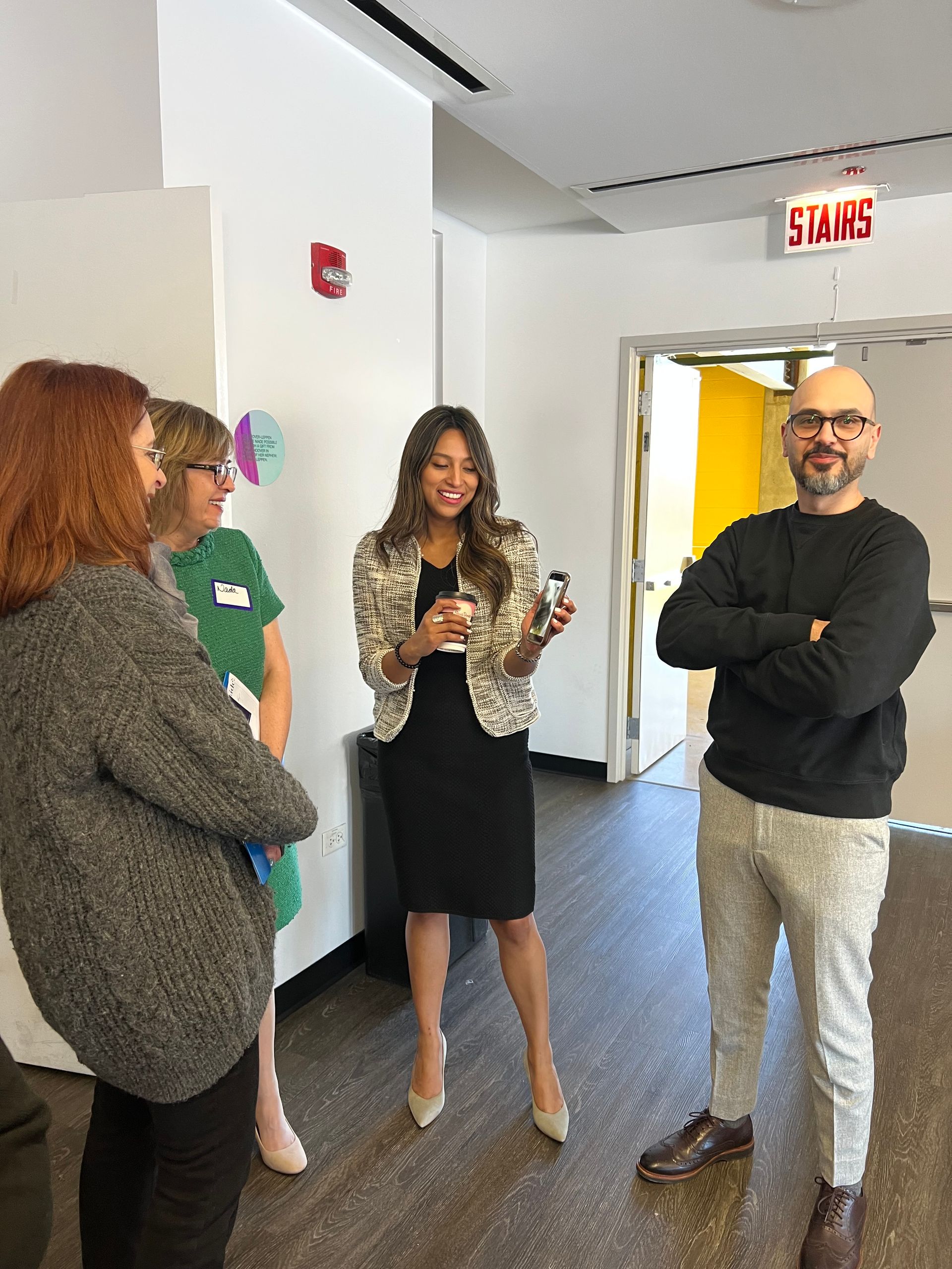 A group of people are standing in a hallway talking to each other.