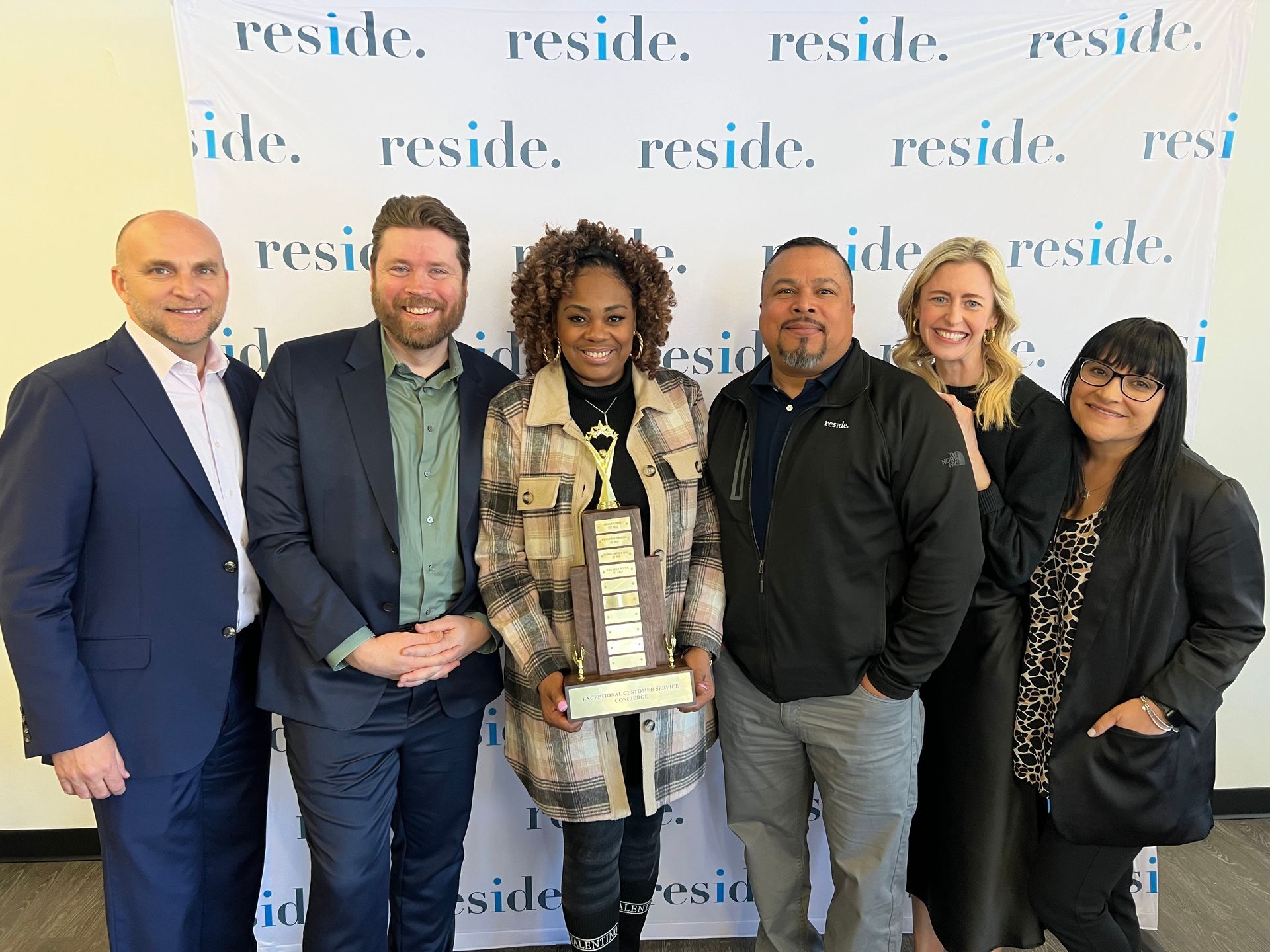 A group of people are posing for a picture with a woman holding a trophy.