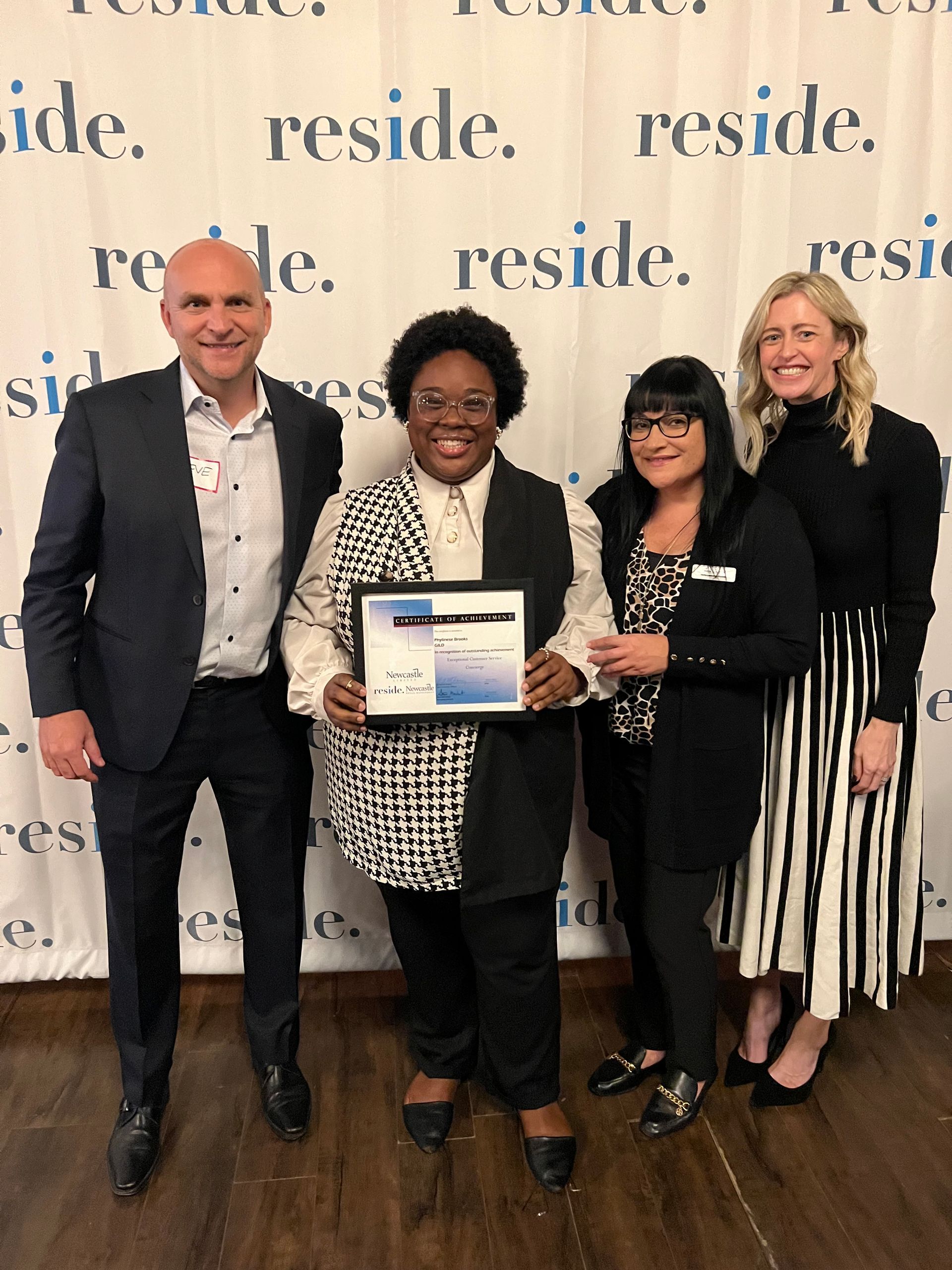 A group of people standing in front of a wall that says reside