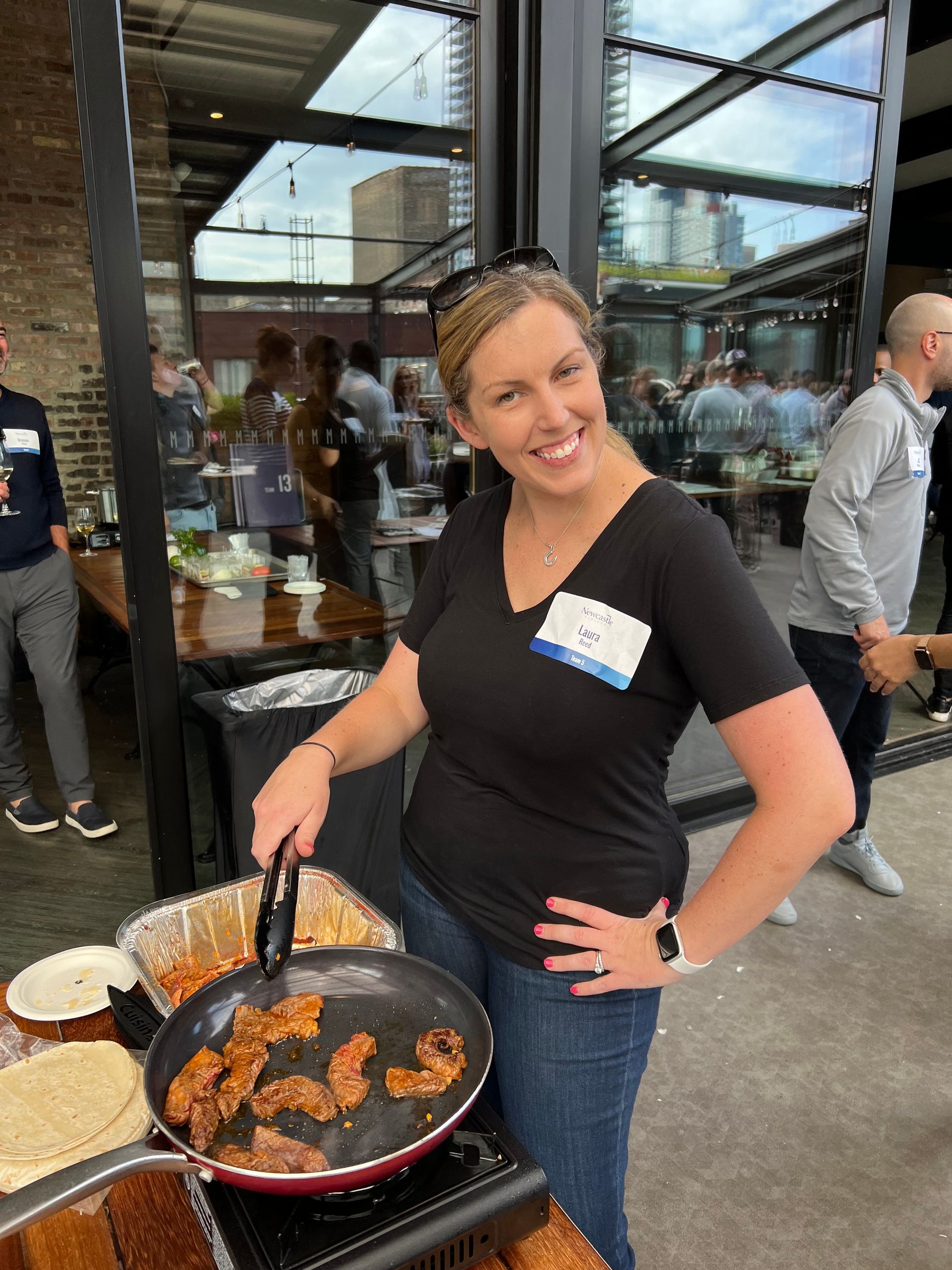 A woman is standing in front of a pan of food.