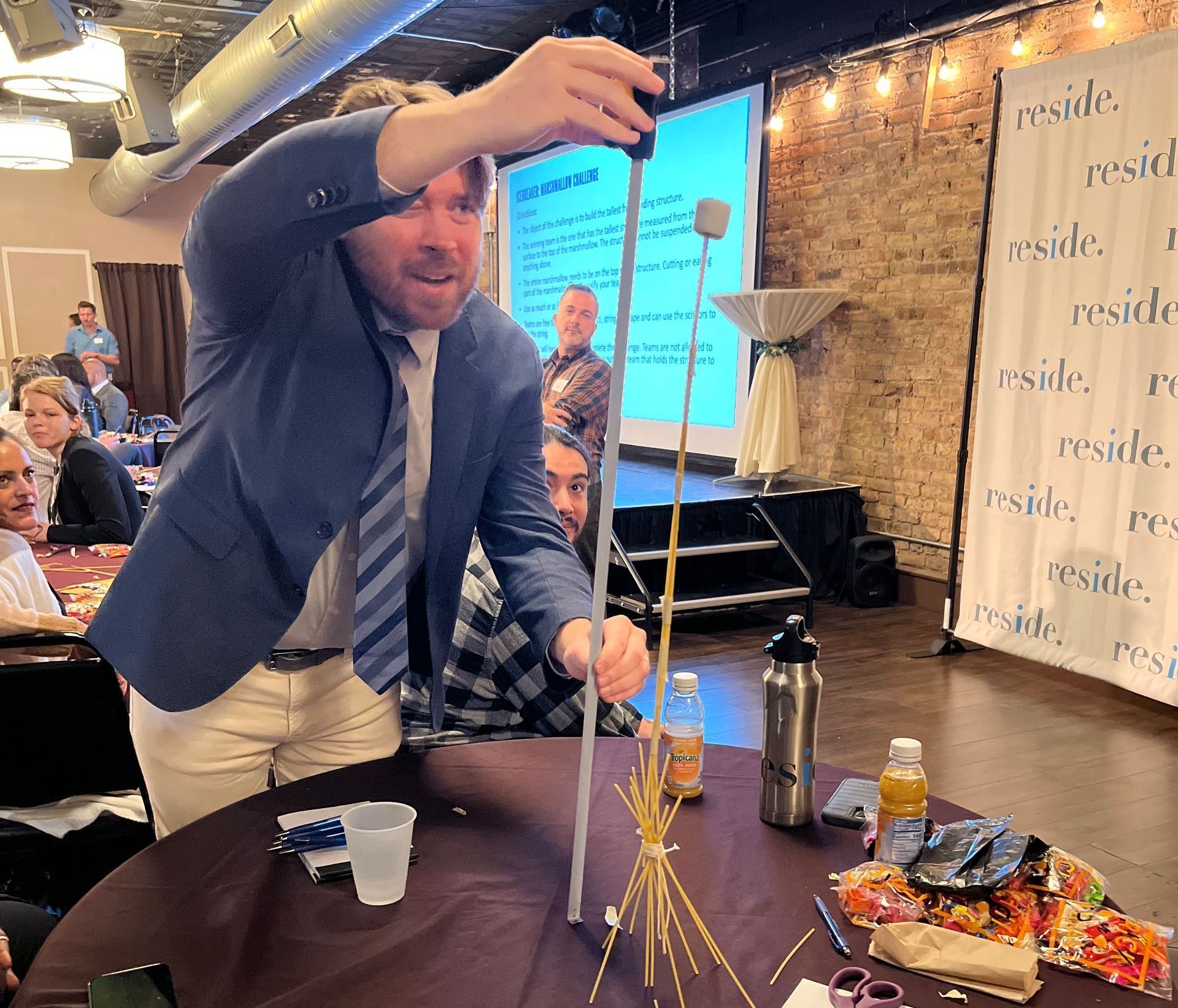 A man in a suit and tie is holding a stick over a table