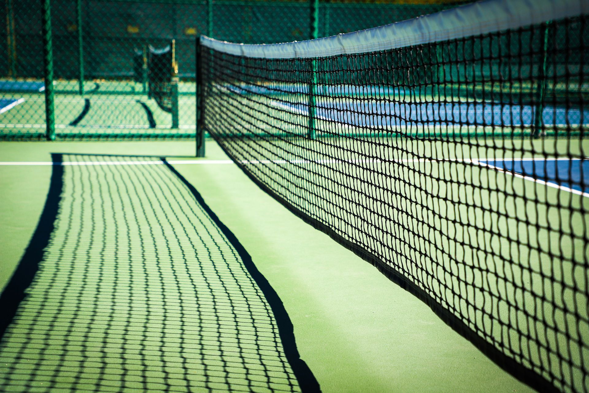 A tennis and pickleball court with a net and a chair in the background.