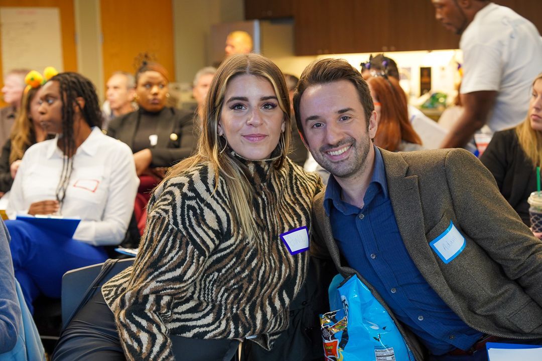 A man and a woman are posing for a picture at a conference.