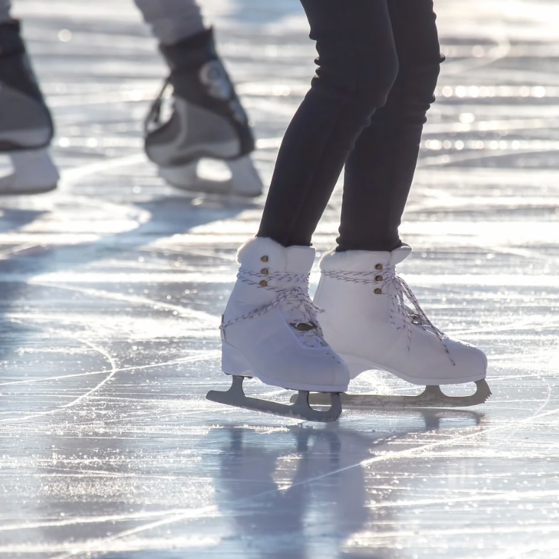 Ice skates on an ice rink. A person in black leggings glides forward.
