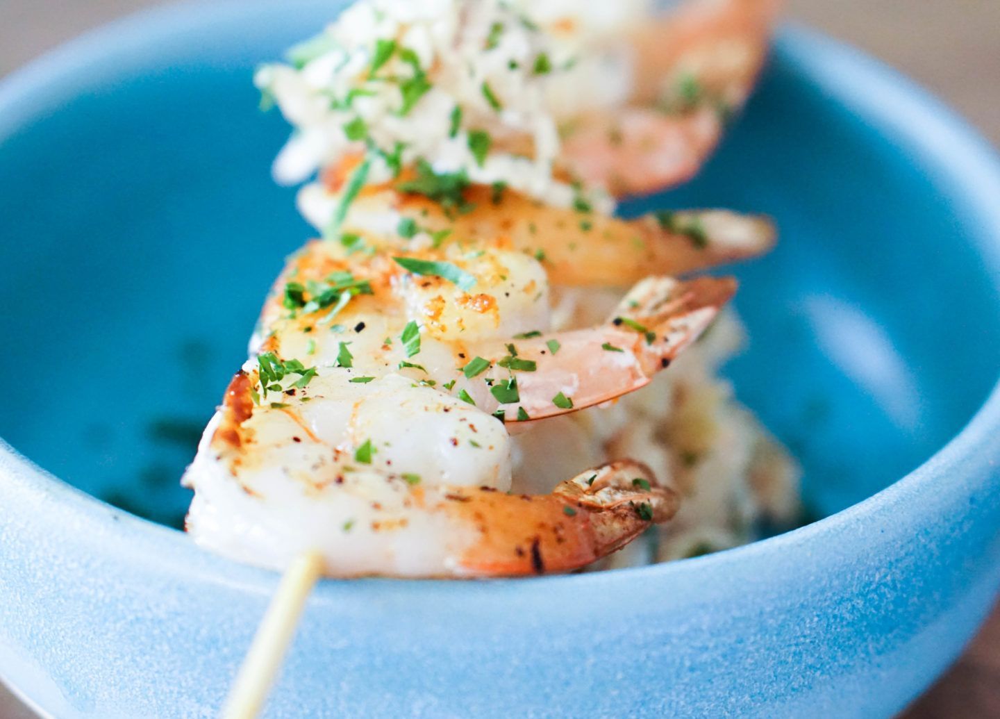 A close up of a bowl of shrimp on a stick