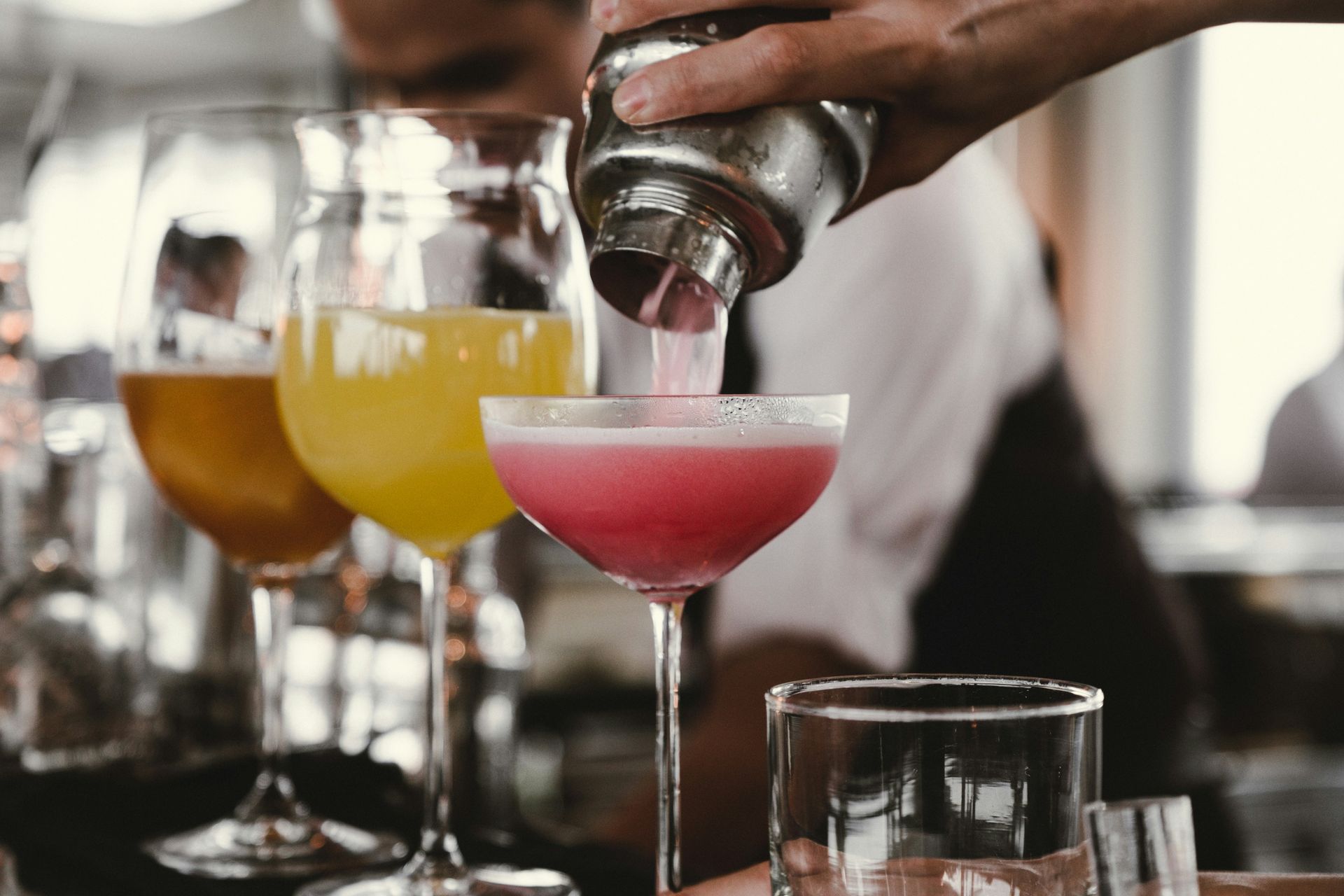 A bartender is pouring a drink into a martini glass.