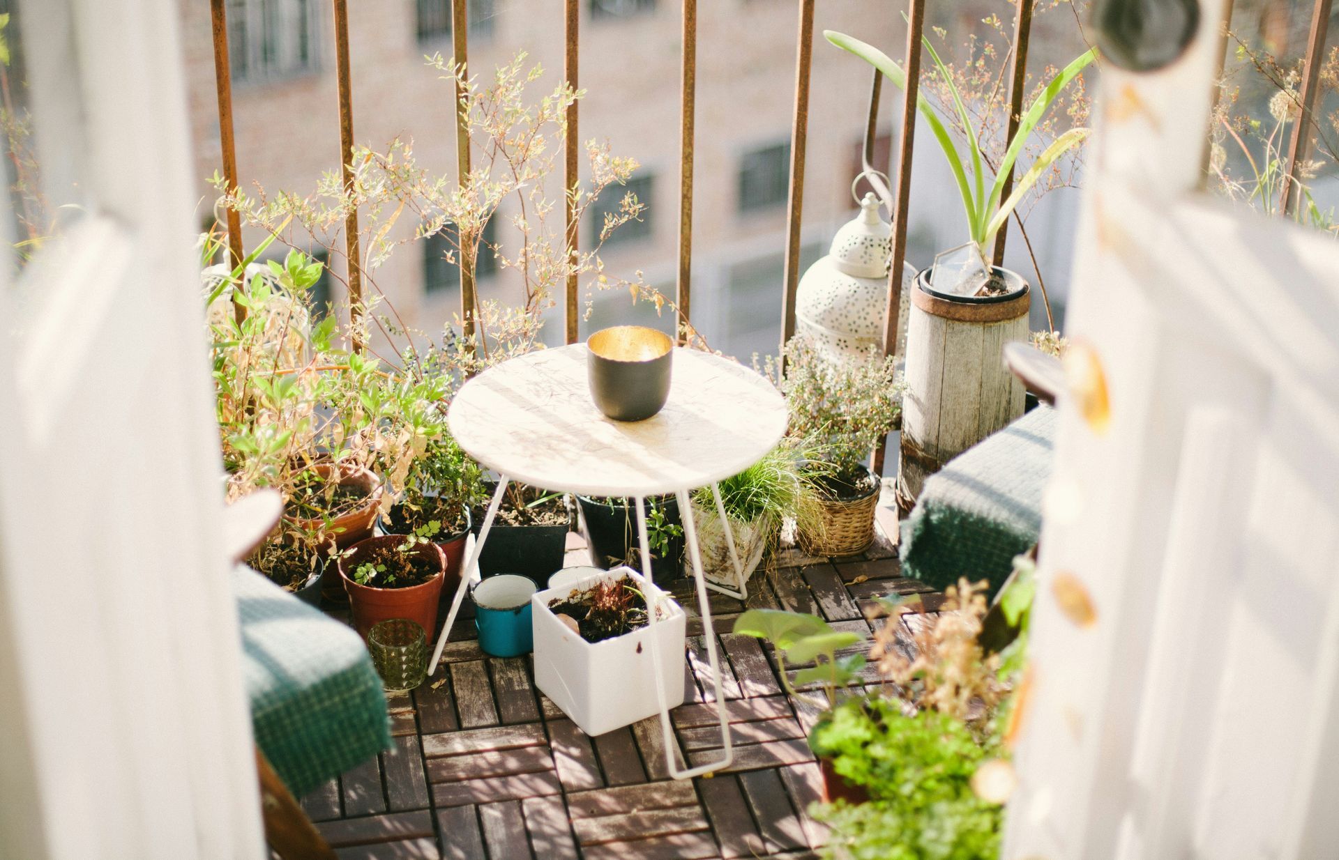 A small balcony with a table and potted plants.