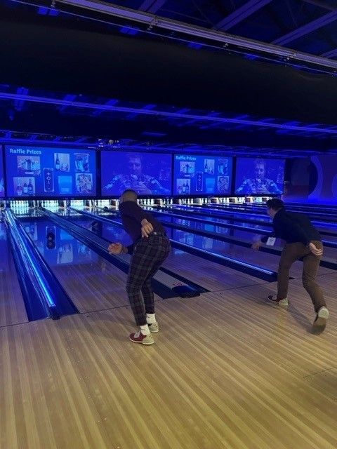 A couple of people are bowling on a bowling alley.