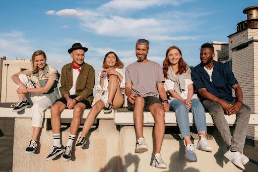 A group of people are sitting on a ledge on top of a building.