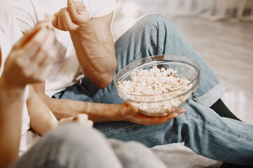 Two people eating a bowl of popcorn.