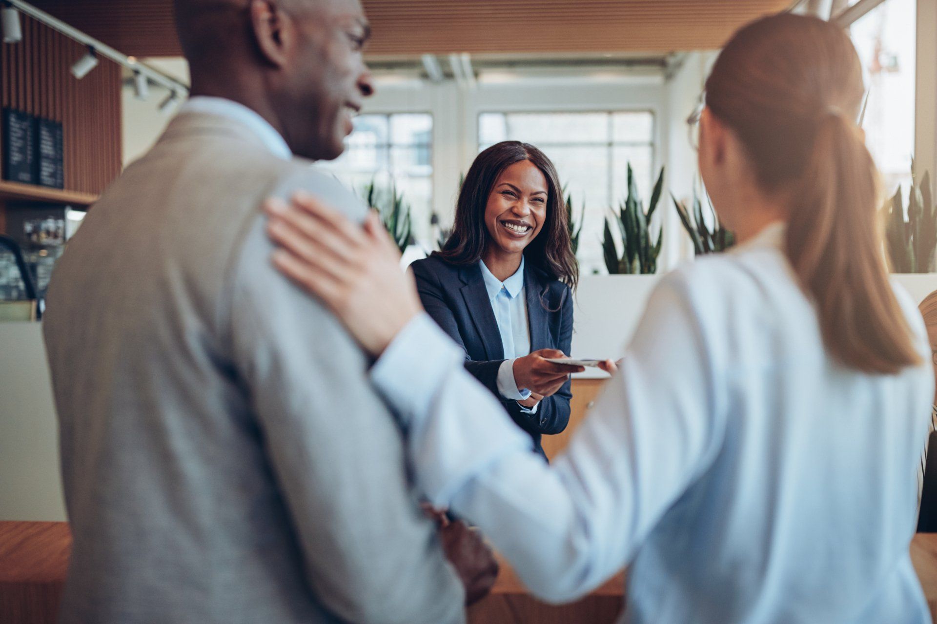 A woman is giving a credit card to a man and woman in a hotel lobby.