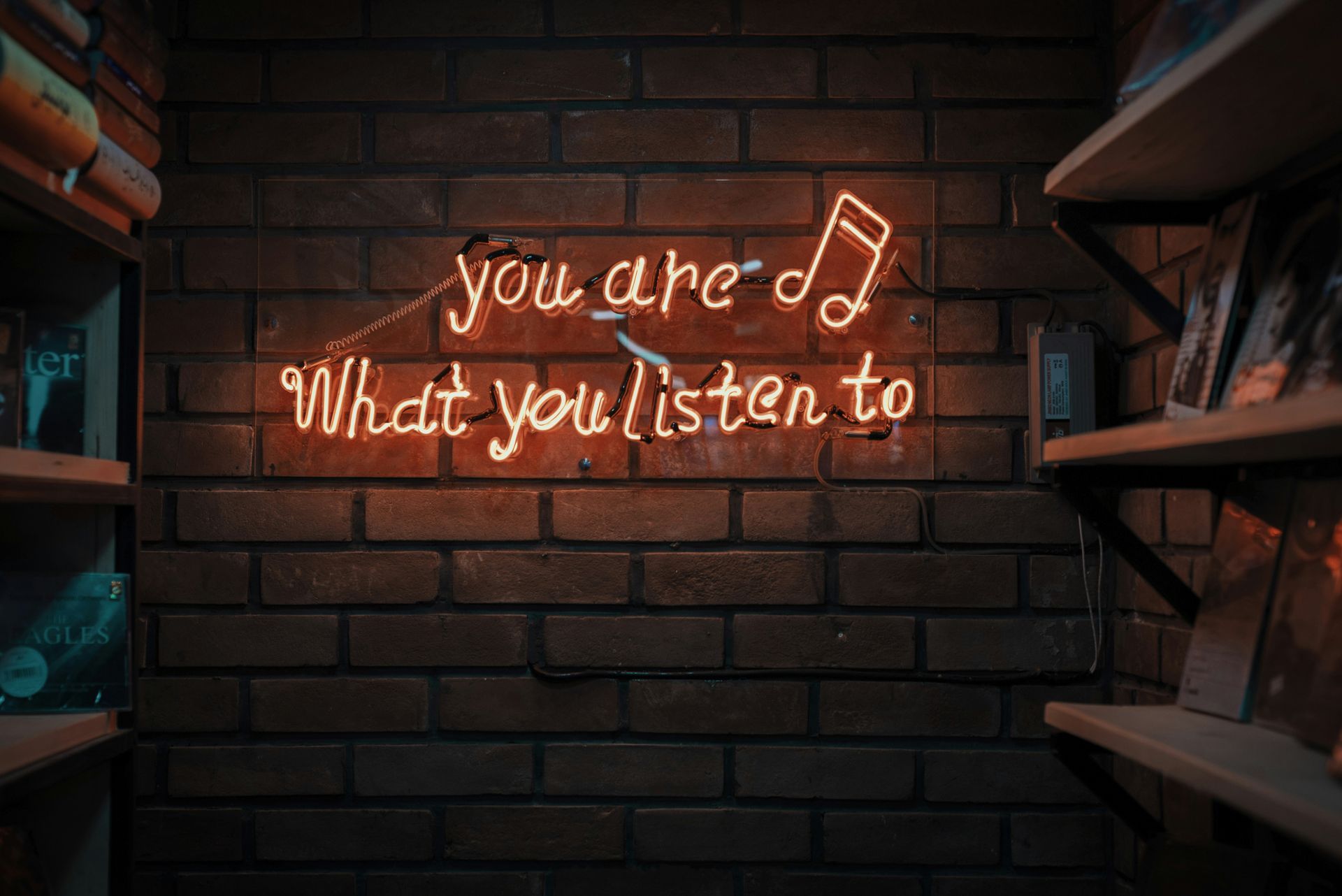 A neon sign on a brick wall says `` you are what you listen to ''.