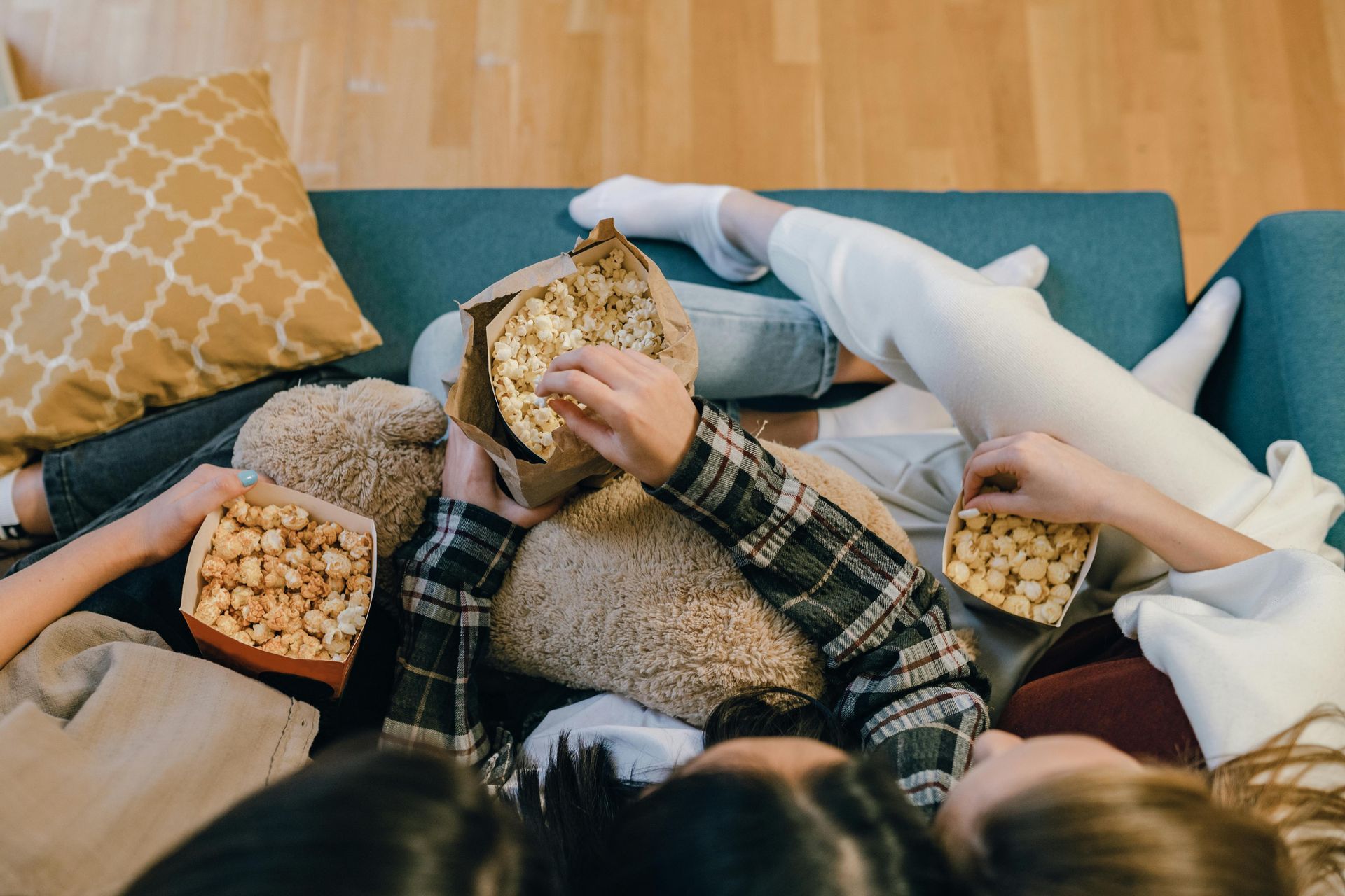 A group of people are laying on a couch eating popcorn.