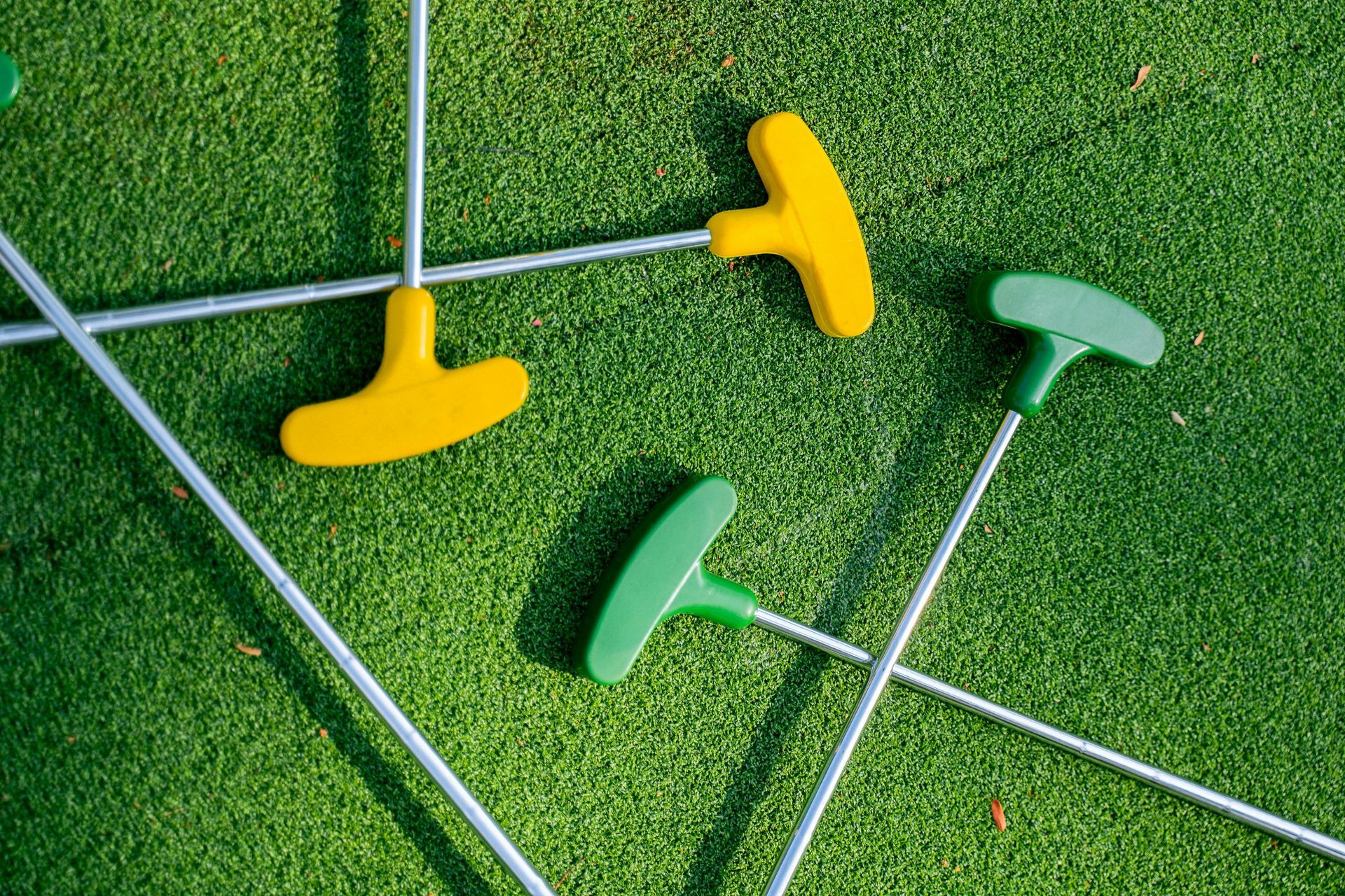 A few putt-putt sticks are on the green grass.