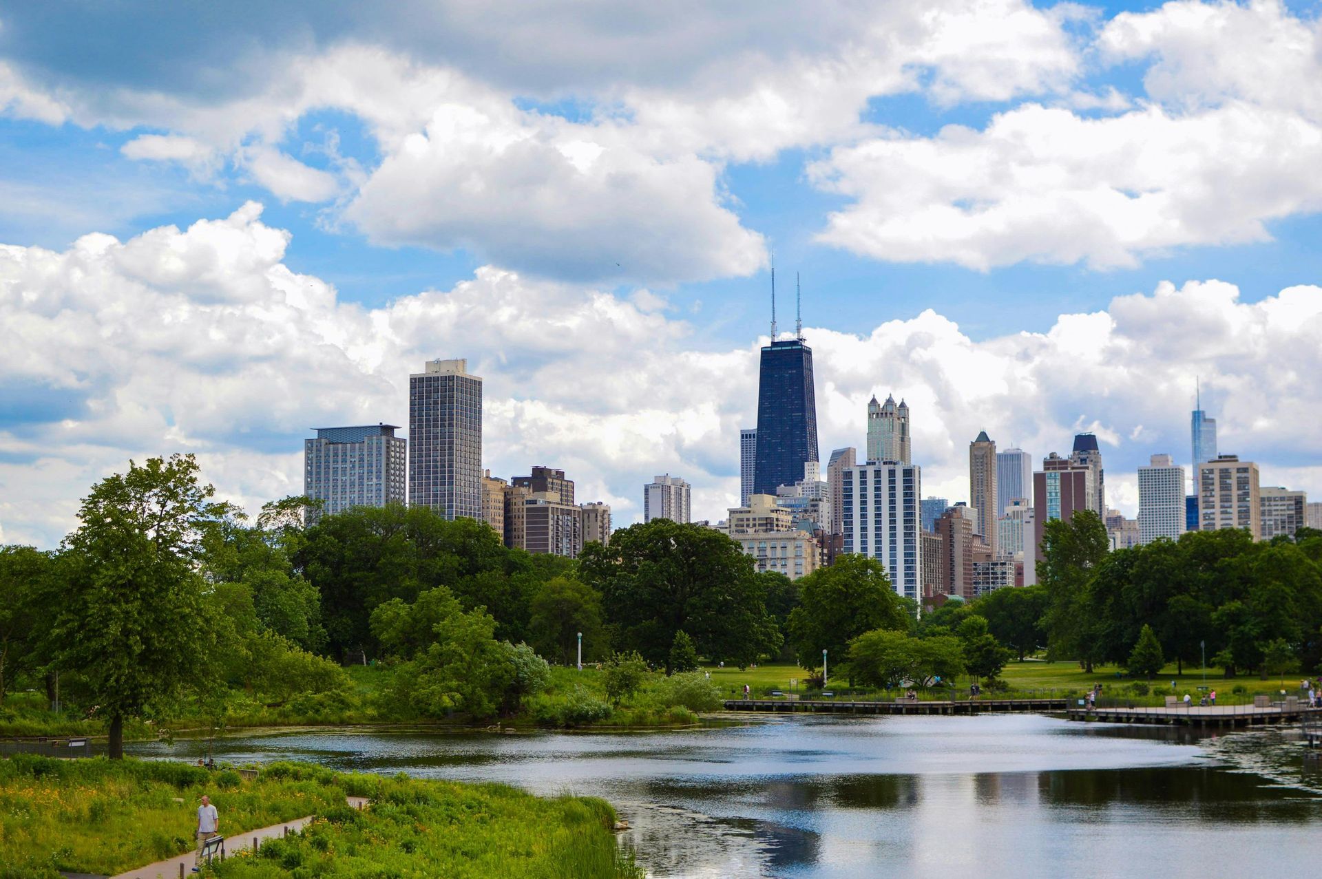 There is a lake in the foreground and a city skyline in the background.