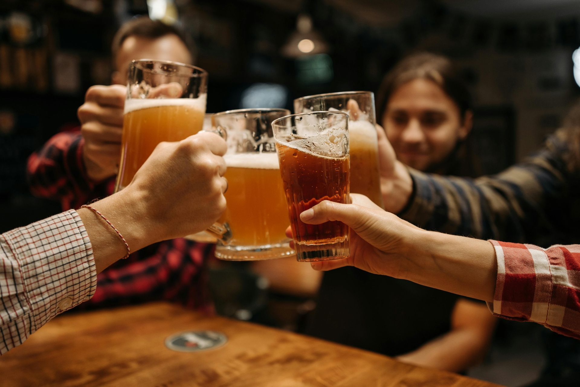 A group of people are toasting with beer glasses in a bar.