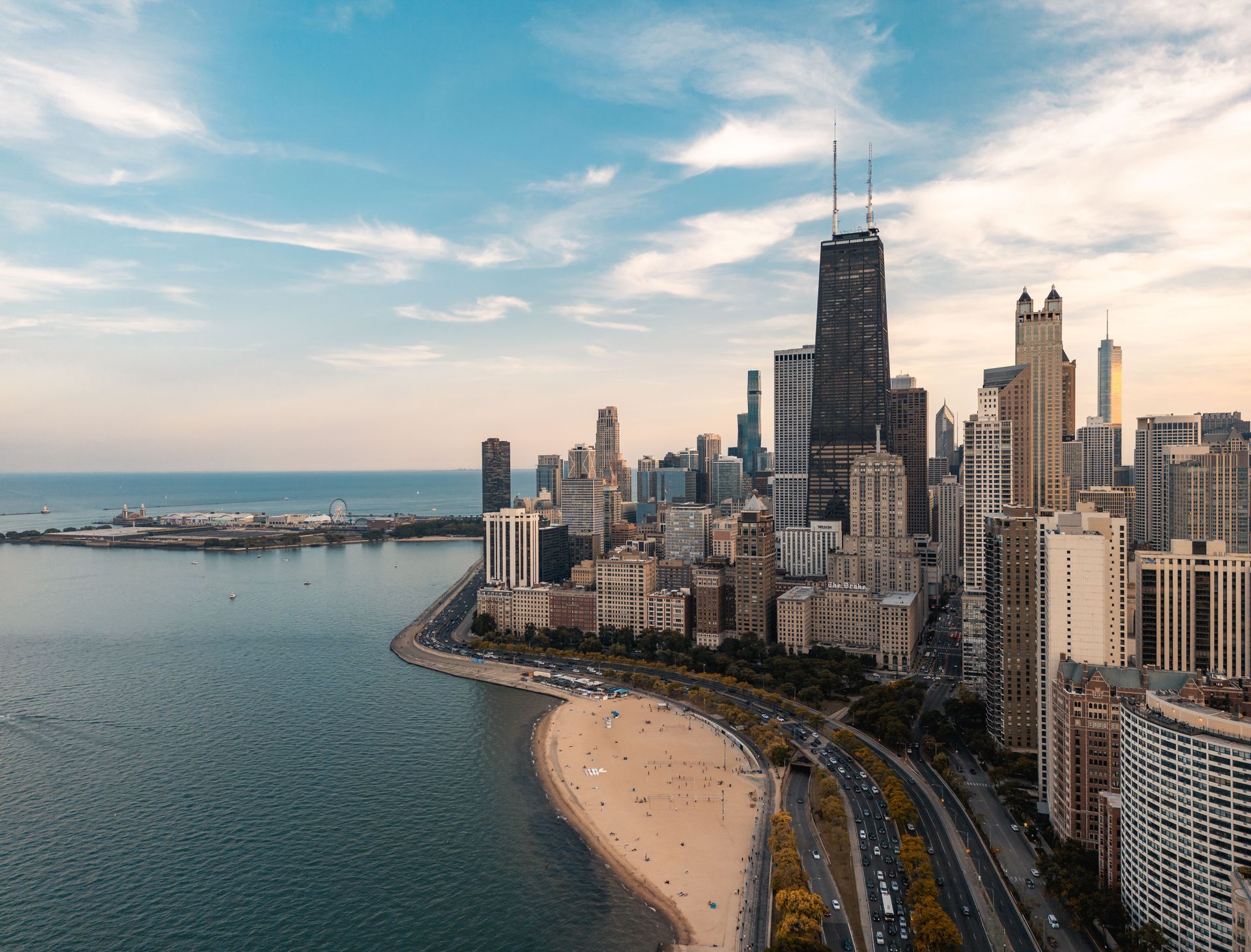Aerial view of Chicago skyline along Lake Michigan with a sandy beach and curving lakeside road