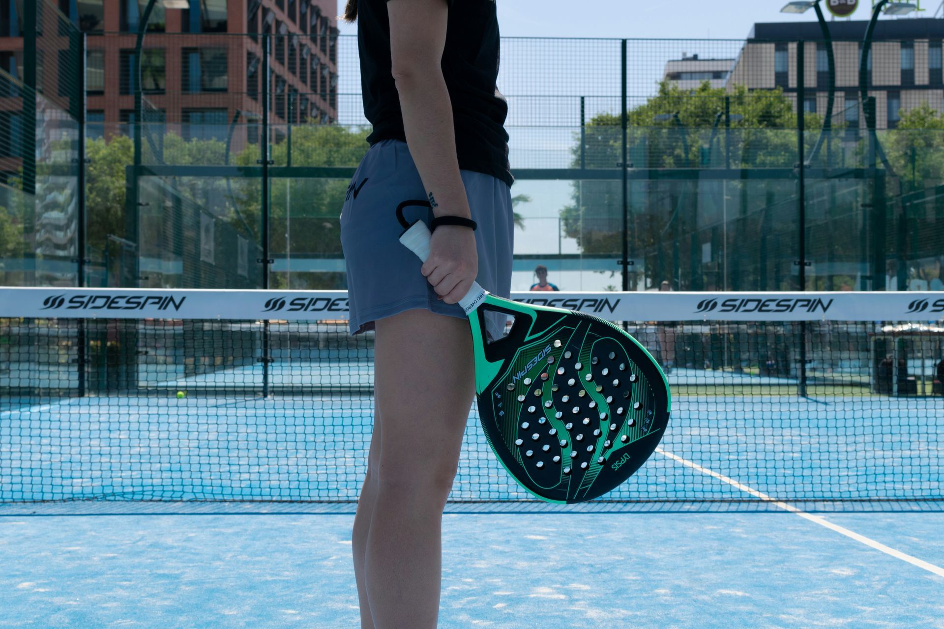 A woman is holding a paddle on a tennis court.