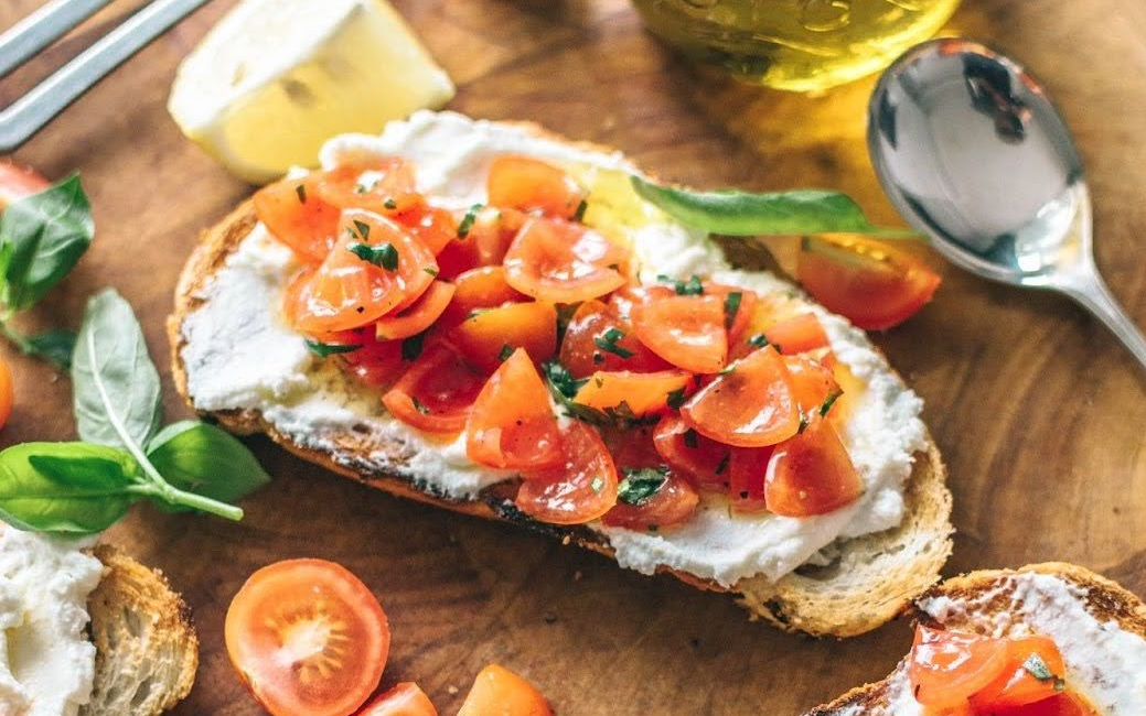 Tomato toast on table with lemon wedge and olive oil