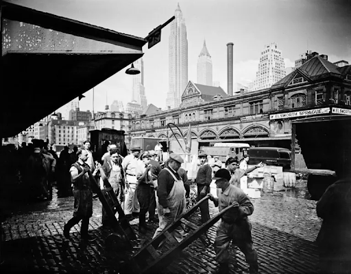 A black and white photo of a group of people pushing carts.