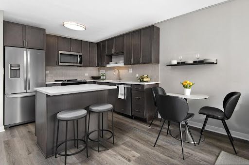 A kitchen with stainless steel appliances , a table and chairs at Reside properties.