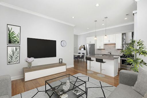 A living room with a couch , television , coffee table and kitchen at Reside properties.