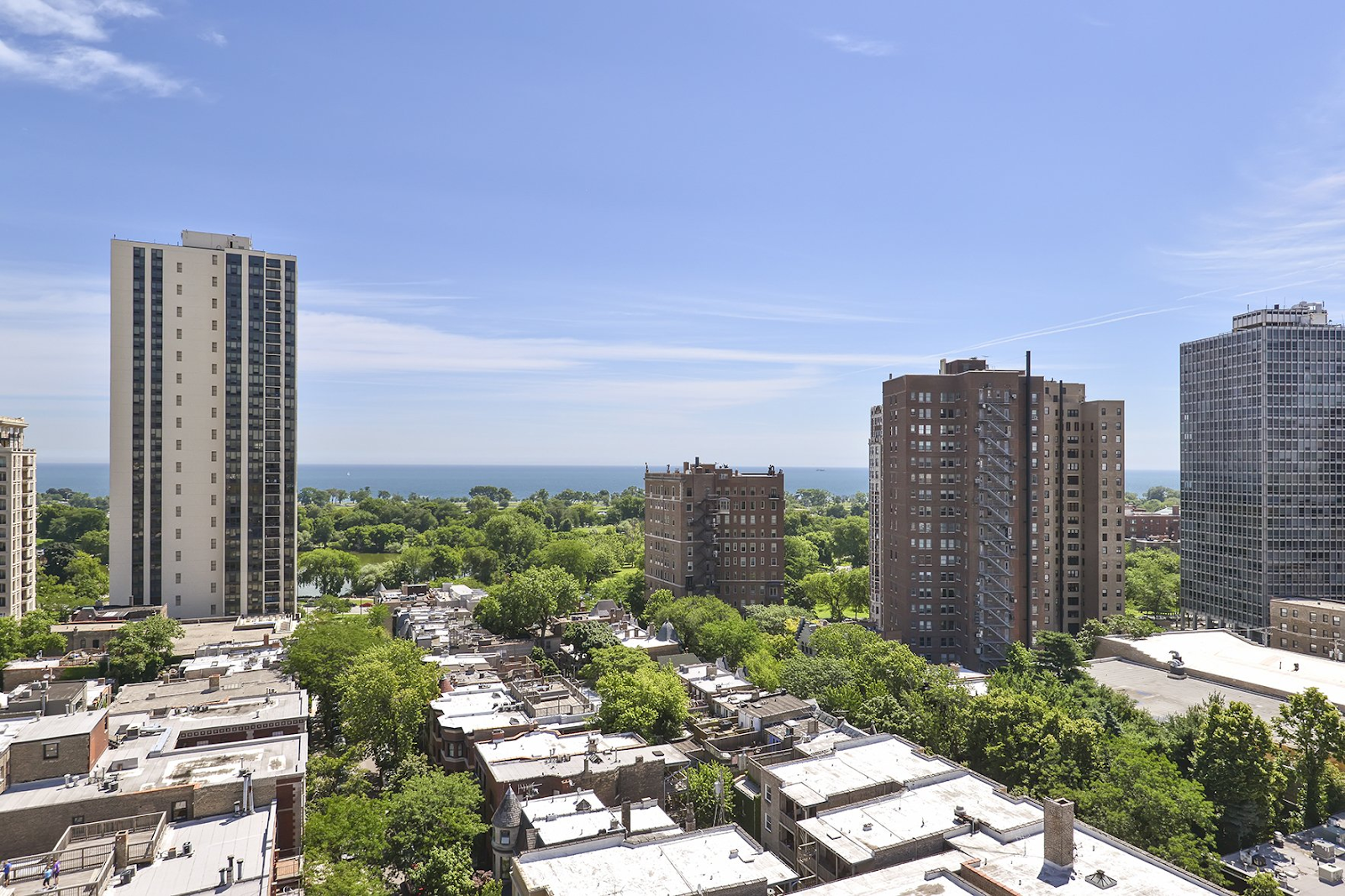 Lincoln Park cityscape with tall buildings, trees, and a view of the water under a blue sky.