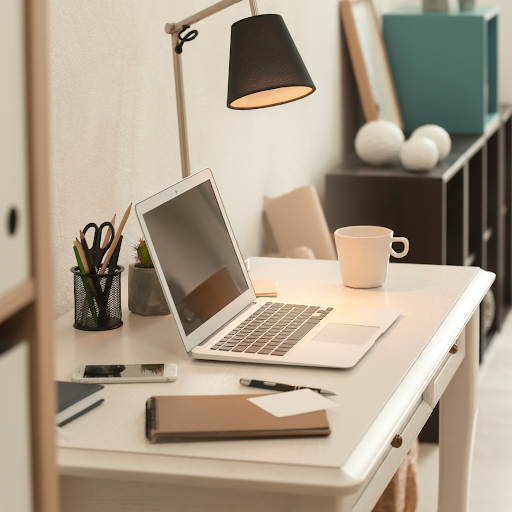 A desk with a laptop and a lamp on it