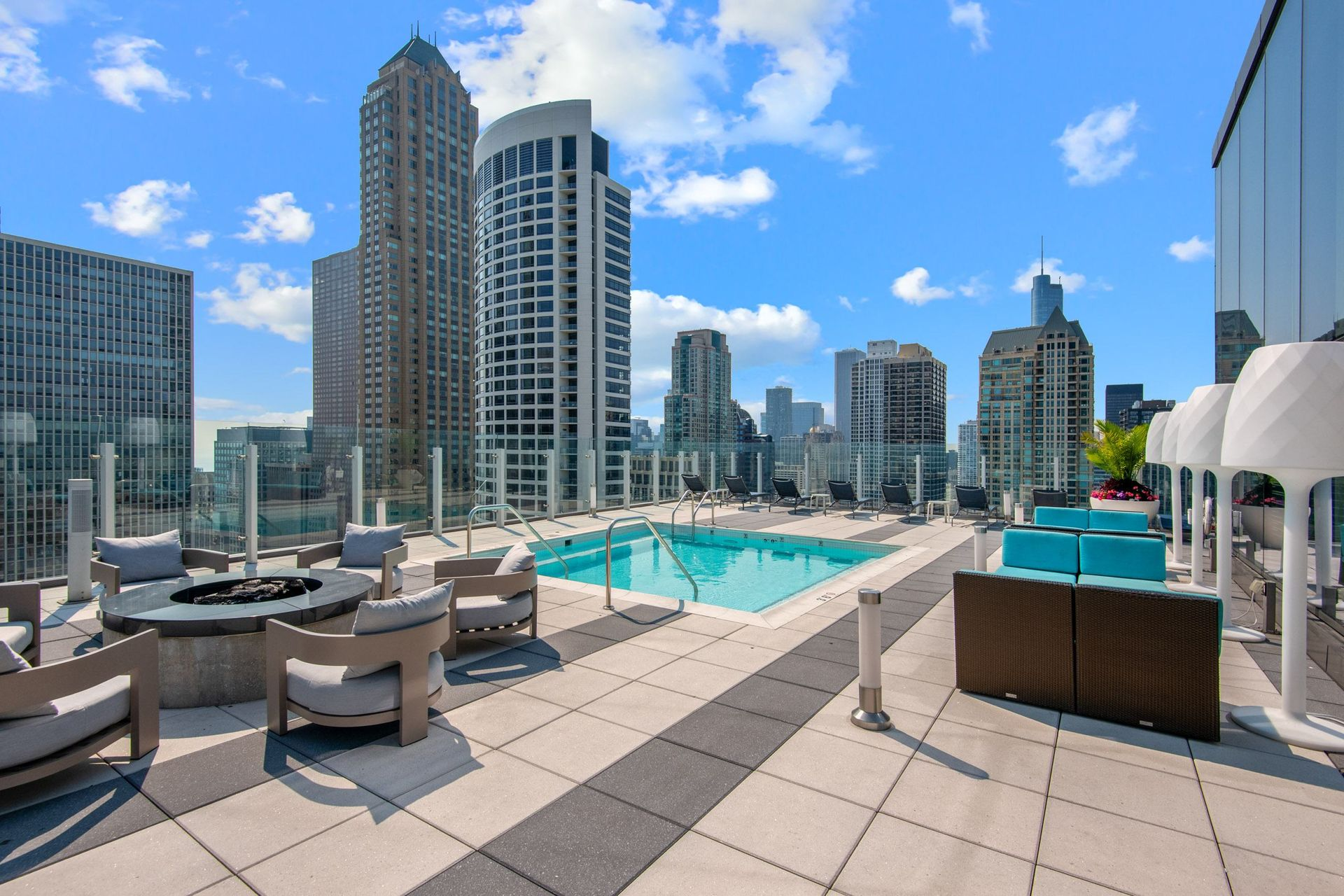 Rooftop pool lounge with city skyline and high-rise buildings under a blue sky