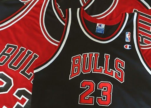 Chicago Bulls basketball jerseys, black and red, featuring the team name, number 23, and Champion logo.