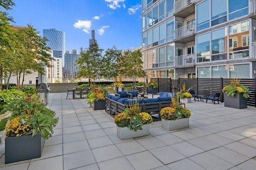 Outdoor patio with seating, planters, and a city skyline backdrop.